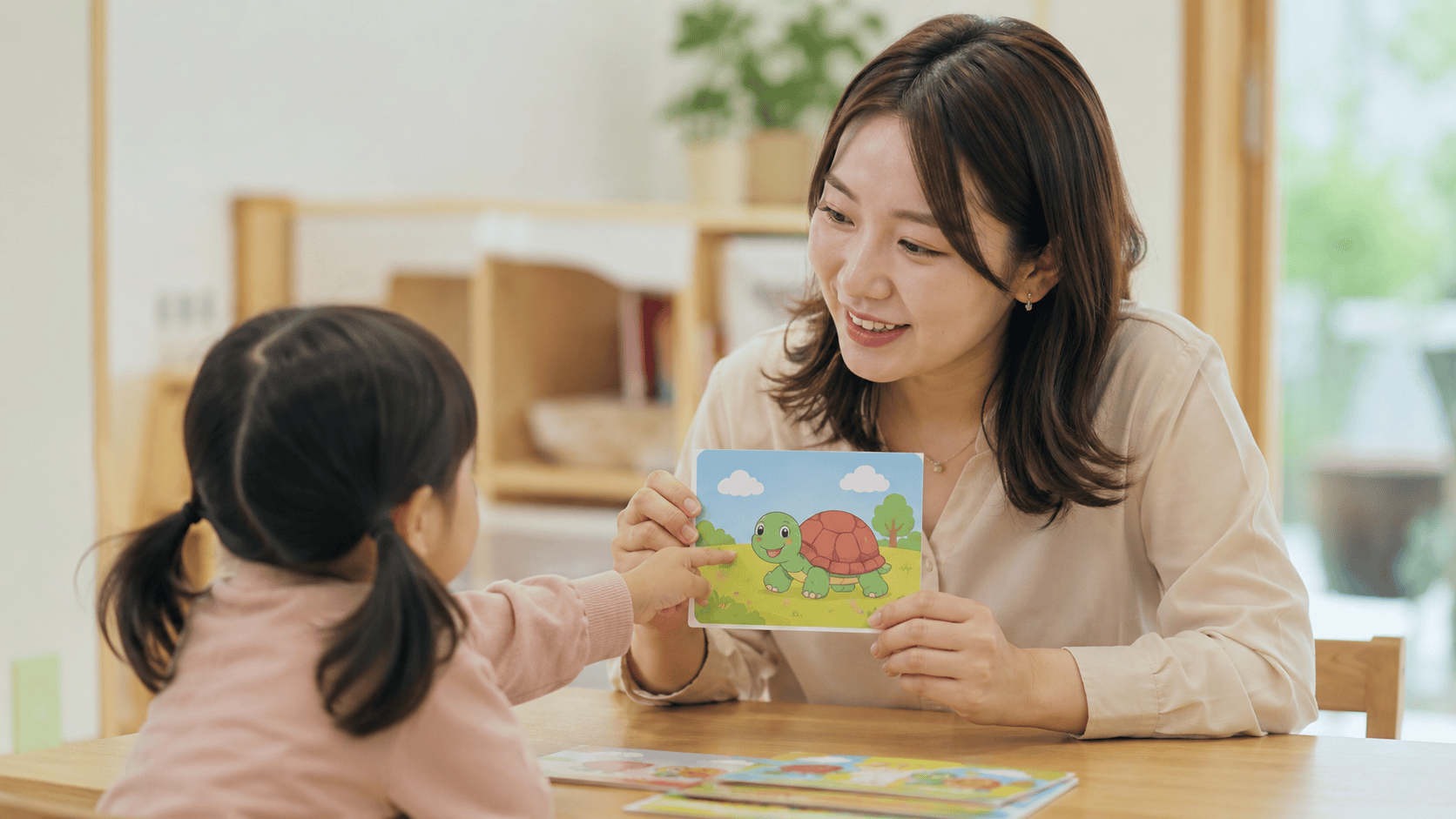 여성 언어치료사가 아동에게 거북이 그림 카드로 언어 치료를 진행한다.