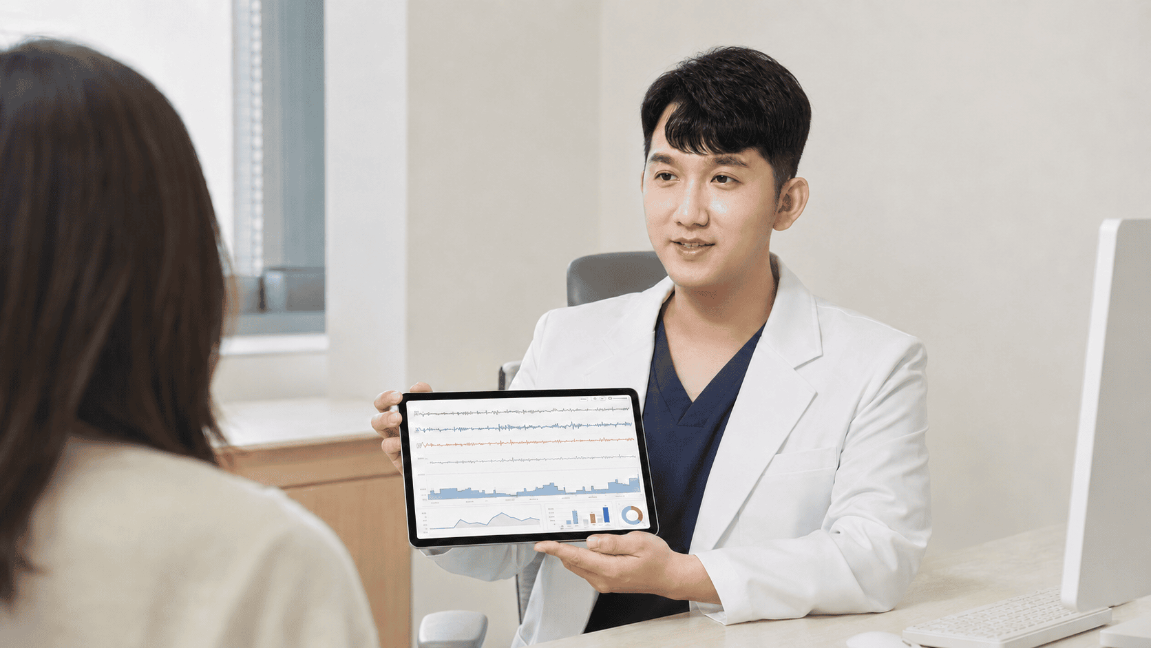 남성 의사가 여성 환자에게 태블릿으로 검사 결과를 설명한다.