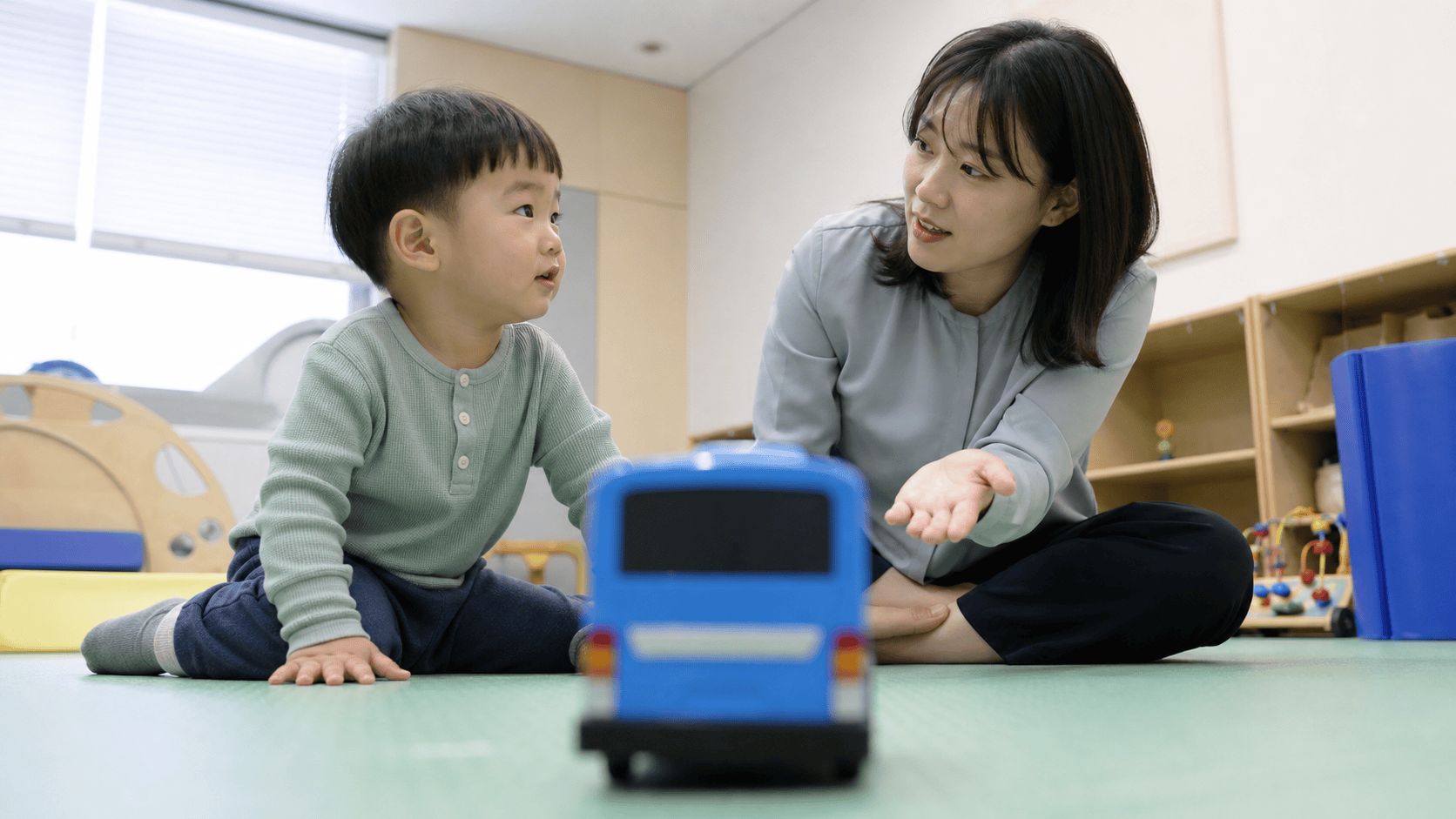 언어치료사가 파란 장난감 버스를 활용해 아이의 호명반응을 이끄는 모습