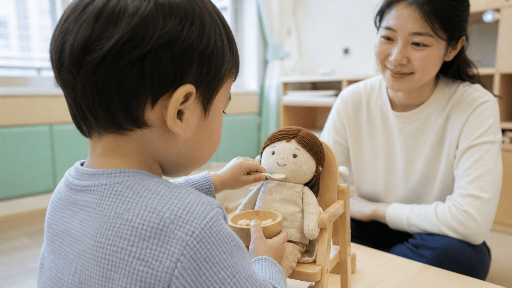 아이가 인형에게 장난감 숟가락으로 밥을 먹이는 상징놀이 장면