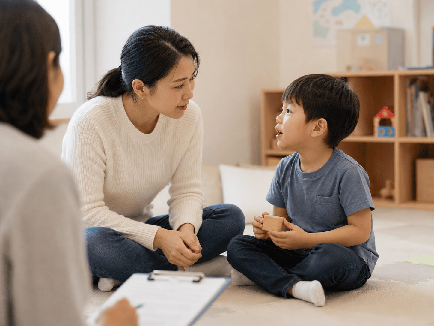 말더듬 치료 중 아동이 성인 여성과 대화하고 다른 성인이 기록한다.