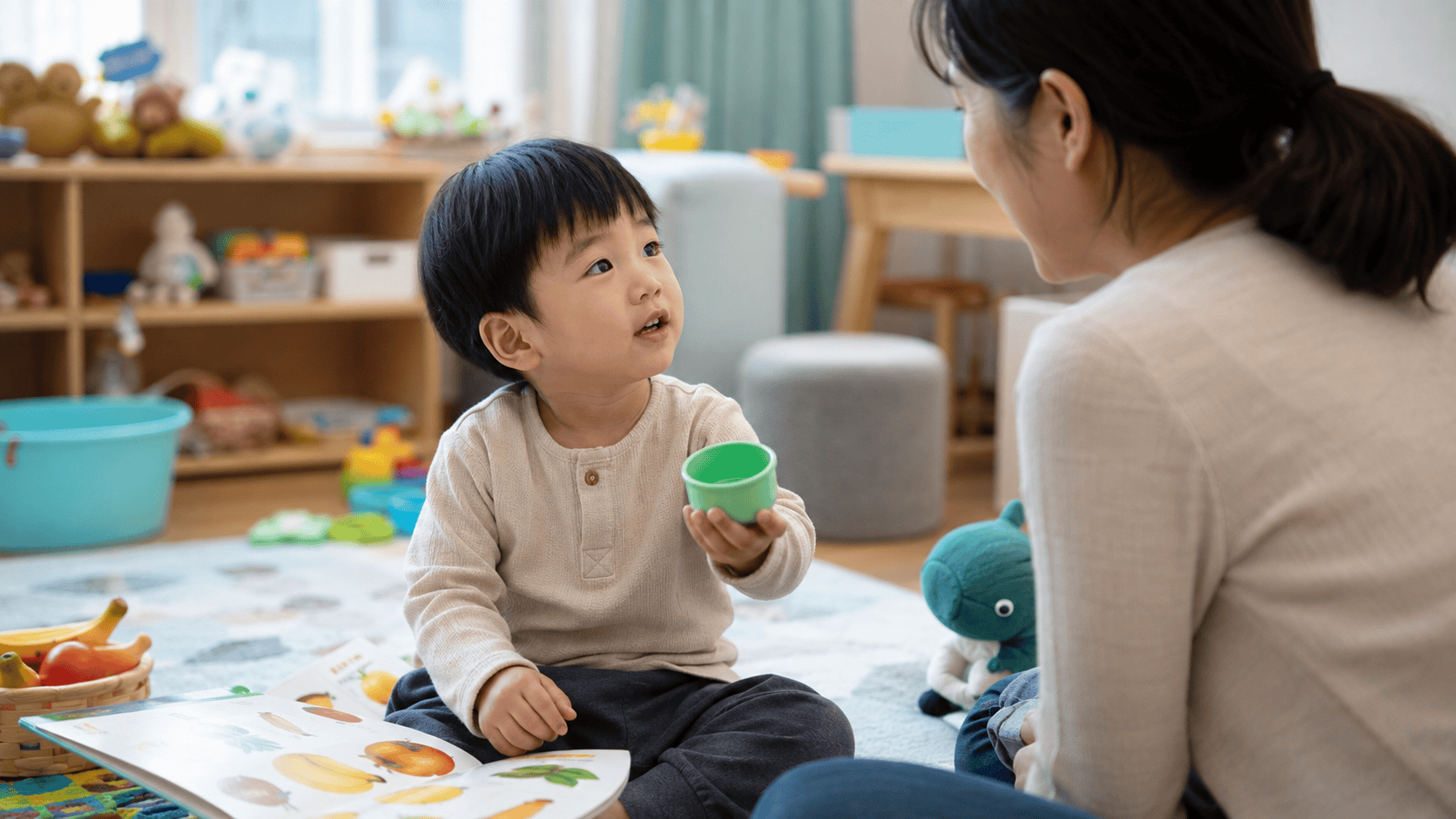 언어치료실에서 아이가 초록 컵을 들고 치료사와 마주 앉아 대화한다.