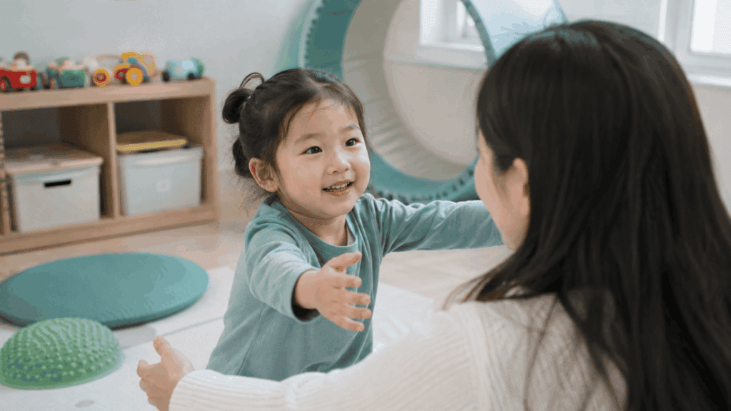 엄마를 바라보며 두 팔을 뻗어 상호작용하는 아이