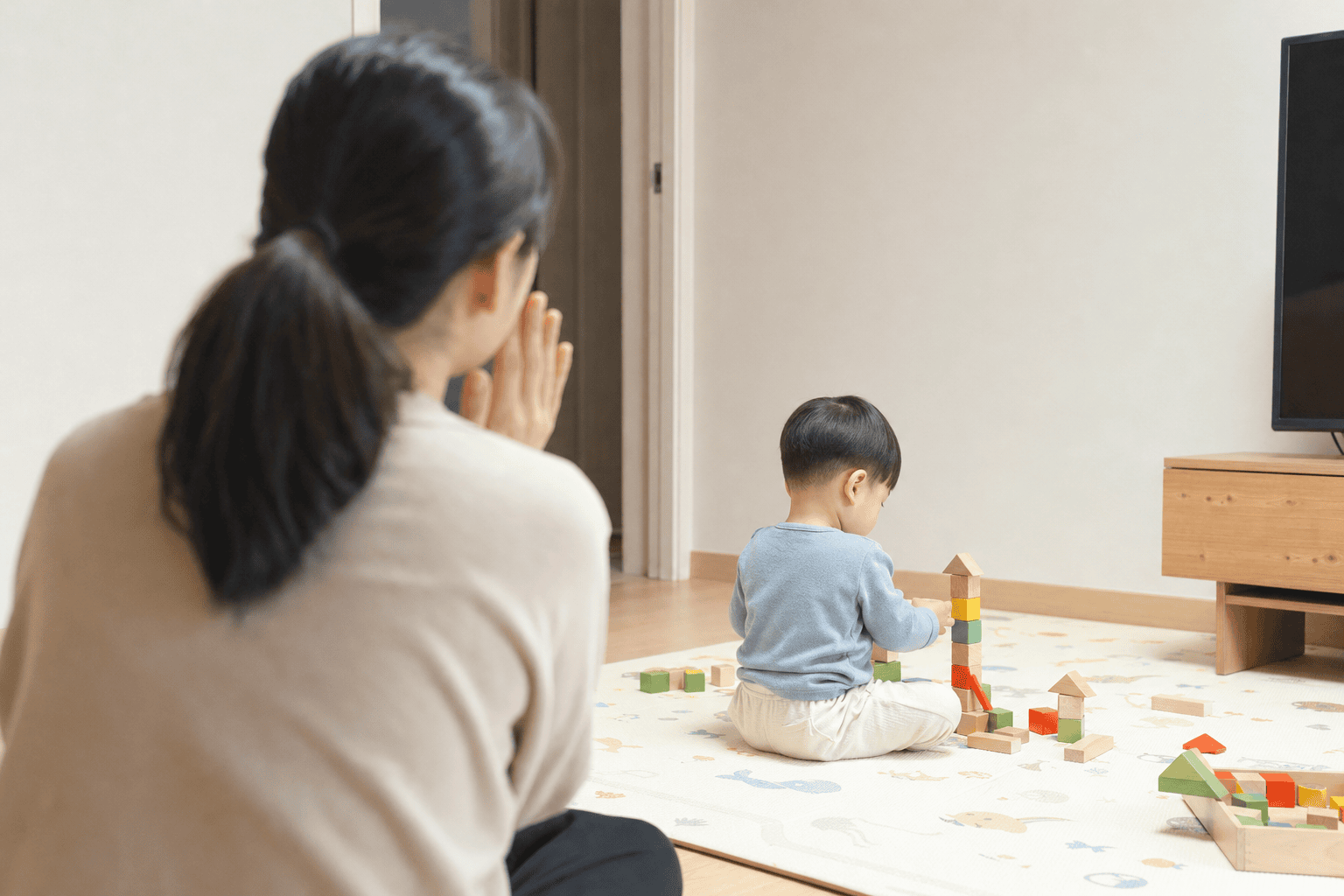 엄마가 뒤에서 부르는 동안 블록을 가지고 노는 아이