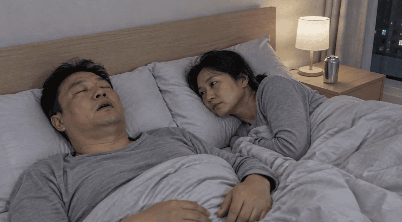 코를 골며 자는 남성과 옆에서 지켜보는 여성